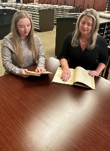Pictured (L to R) are Tiffany Couch, Deputy Court Clerk Supervisor examining the Christiansburg District Tax Book 1914. Erica W. Conner, Clerk examining the Town of Christiansburg Minute Book 1854 – 1861.