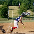 A softball player bunts the ball in front of home plate and begins her run towards first base.